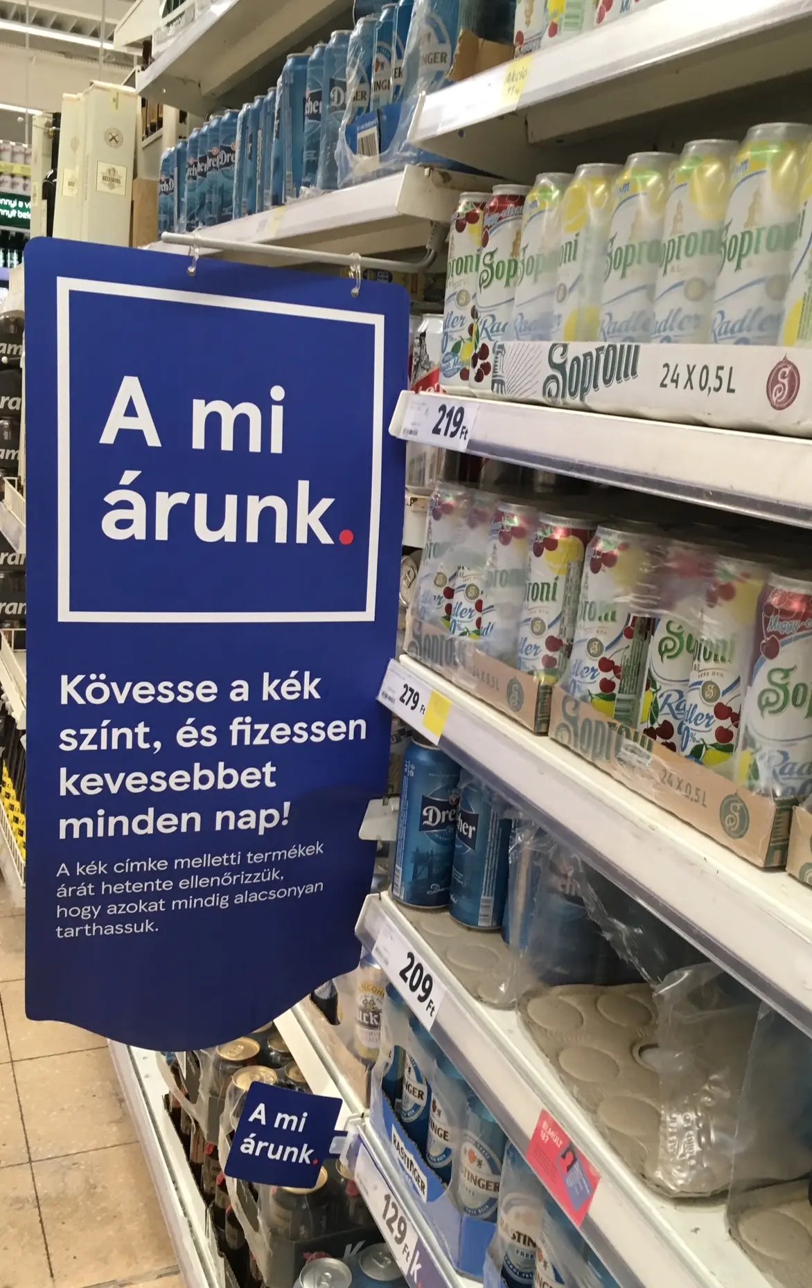 „A mi árunk” polc-él árjelző tábla Soproni üvegek mellett